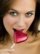 Woman biting a heart-shaped chocolate