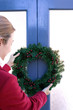 Girl putting up a wreath on the door