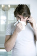 A man blowing his nose while on the phone