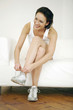 Woman sitting on the couch tying her shoelace