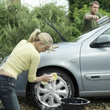 Woman washing car wheel, man washing windshield with squeegee
