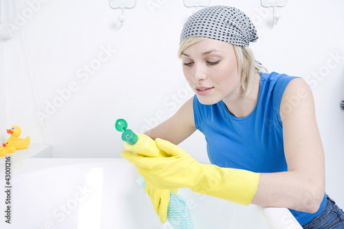 Photo: Woman with rubber gloves reading instructions on cleaning detergent Woman with rubber gloves reading instructions on cleaning detergent
