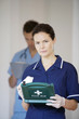 Nurse with a first aid kit with a male doctor in the background