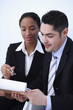 Businessman and businesswoman reading from the clipboard