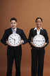 Businessman and businesswoman holding clocks