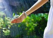 Female's hand under the raindrops