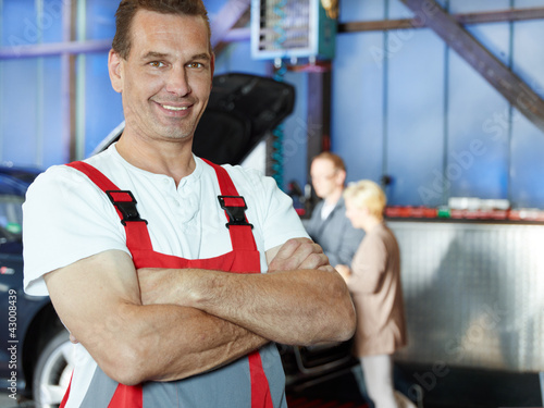 Photo: Master mechanic in a garage is proud of his work Master mechanic in a garage is proud of his work