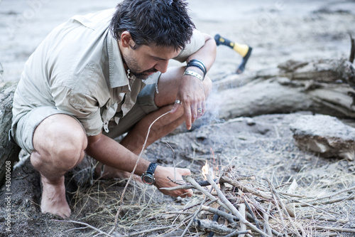Photo: man making a fire on the beach by the river - series man making a fire on the beach by the river - series