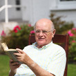 Happy pensioner relaxing with a book sitting in his garden