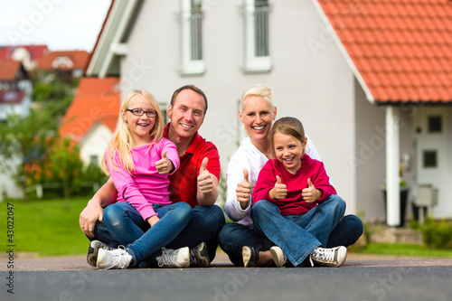 Photo: Familie sitzt vor ihrem Haus Familie sitzt vor ihrem Haus