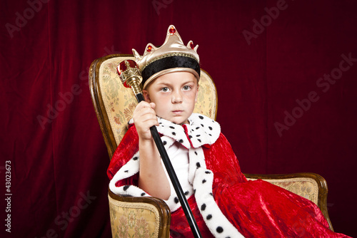 Foto: little boy dressed ad a king on red velvet background little boy dressed ad a king on red velvet background