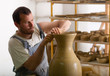 Craftsman making vase from fresh wet clay on pottery wheel