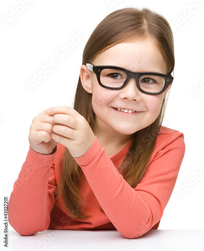 Foto: Happy little girl sits at a table and smile Happy little girl sits at a table and smile