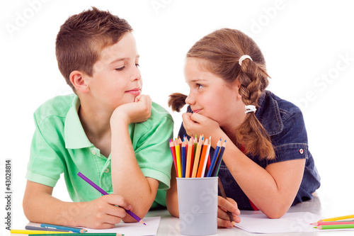 Photo: Two children draw with colorful crayons and smile, isolated over Two children draw with colorful crayons and smile, isolated over