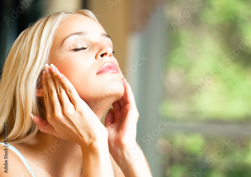 Photo: Happy smiling woman applying creme, indoor Happy smiling woman applying creme, indoor