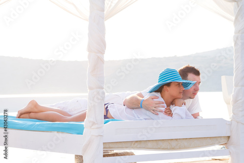 Photo: Couple lying on luxury white bed at the sea Couple lying on luxury white bed at the sea