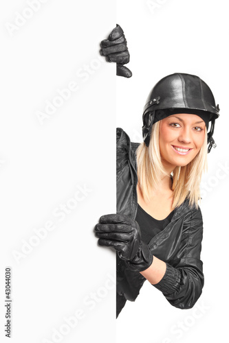 Photo: A portrait of a smiling female motorcyclist holding a blank pane A portrait of a smiling female motorcyclist holding a blank pane