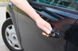 Driver`s hand opening car door of black land vehicle