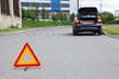 Triangle warning sign on road foreground and car with lights