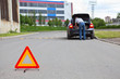 Photo: Triangle warning sign on road and car with blinker lights on way Triangle warning sign on road and car with blinker lights on way