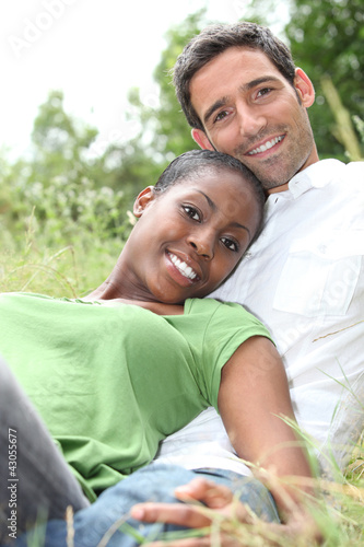 Photo: An interracial couple lying on grass. An interracial couple lying on grass.