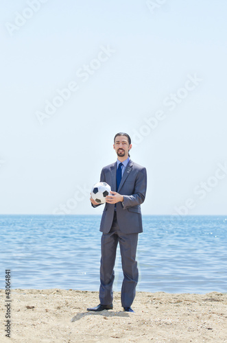 Photo: Businessman with football on beach Businessman with football on beach