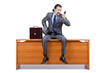 Businessman sitting on desk and speaking phone