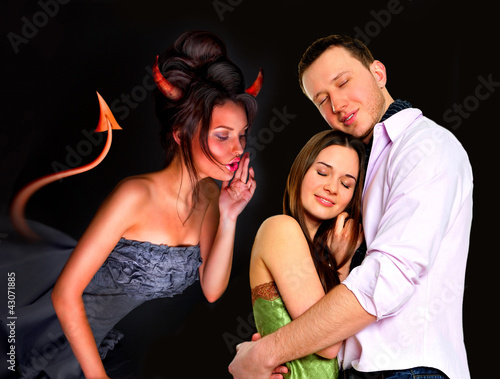 Photo: Young couple embracing in love. Devil whispering wrong things to Young couple embracing in love. Devil whispering wrong things to