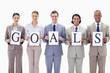 Happy business team holding the letters of GOALS