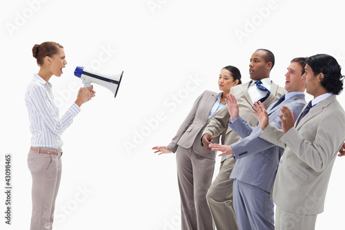 Photo: Woman yelling at business people through a megaphone Woman yelling at business people through a megaphone