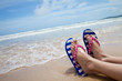Young girl legs in colorful flipflop sandals on sea beach