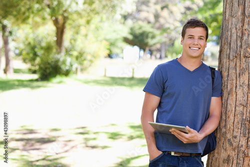 Foto: Portrait a student leaning against a tree Portrait a student leaning against a tree