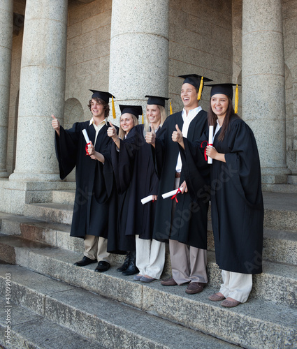 Foto: Laughing graduates posing the thumb-up Laughing graduates posing the thumb-up