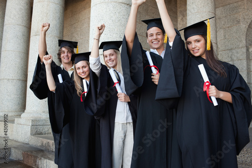 Photo: Five happy graduates posing the arm raised Five happy graduates posing the arm raised