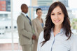 Young smiling businesswoman standing in front of her colleagues
