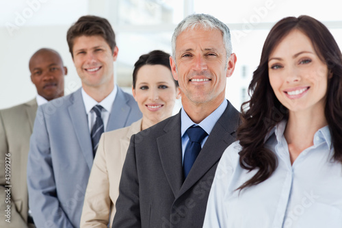 Photo: Four smiling employees standing upright around their director Four smiling employees standing upright around their director