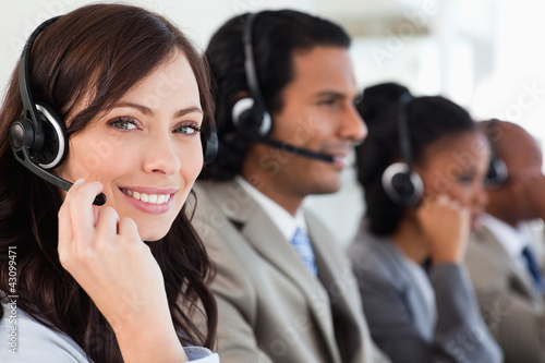 Foto: Smiling employee working with a headset while looking at the cam Smiling employee working with a headset while looking at the cam
