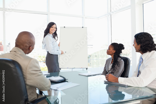 Photo: Businesswoman giving a presentation while her co-workers are lis Businesswoman giving a presentation while her co-workers are lis