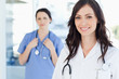 Smiling nurse accompanied by her colleague in the background