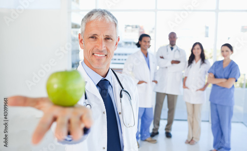 Photo: Medical team in the background looking at a doctor who is holdin Medical team in the background looking at a doctor who is holdin