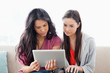 Two women on the couch looking at a tablet together