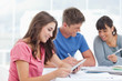 A girl looks at the tablet screen as she smiles with friends