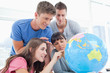 Students pointing to places in the world on a globe