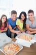 Friends sitting on a couch about to eat pizza