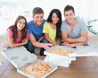 Photo: Four friends smile and face the camera as they sit in front of p Four friends smile and face the camera as they sit in front of p