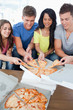 A group grabbing themselves a slice of the pizza