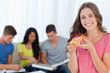A smiling girl with a slice of pizza in front of her friends