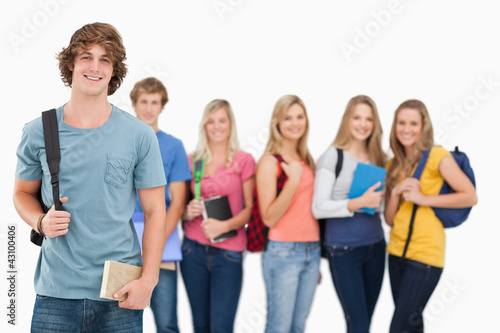 Photo: A man standing in front of his friends as he smiles A man standing in front of his friends as he smiles