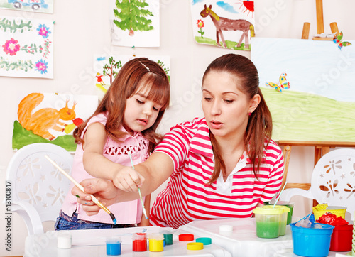 Photo: Child with teacher draw paints in play room. Child with teacher draw paints in play room.