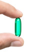 Photo: Male hand holding green pill isolated on white background Male hand holding green pill isolated on white background